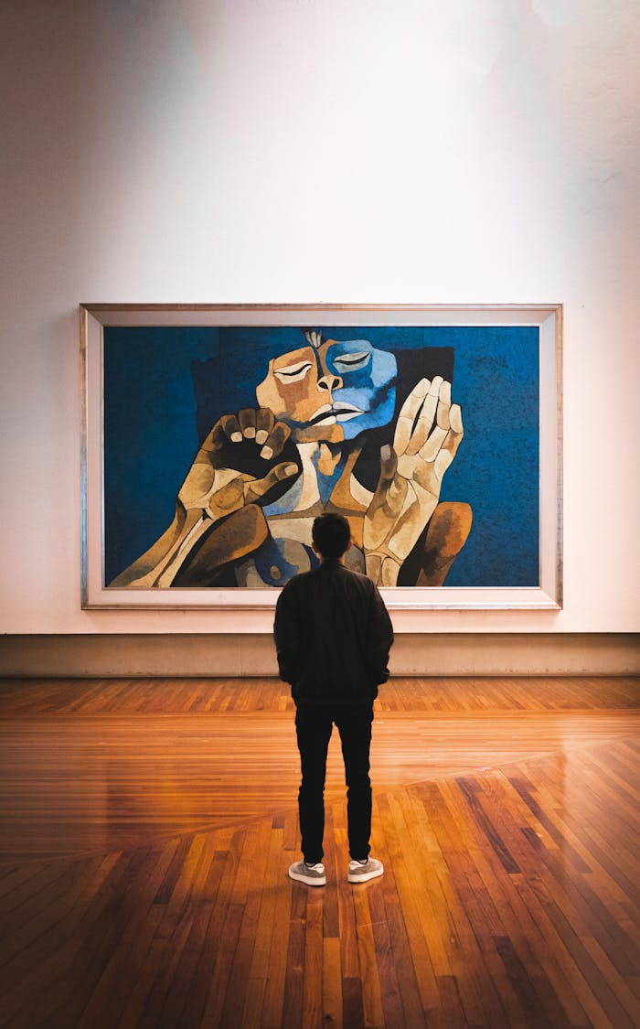 A man stands admiring an abstract painting in a gallery, highlighting cultural appreciation.